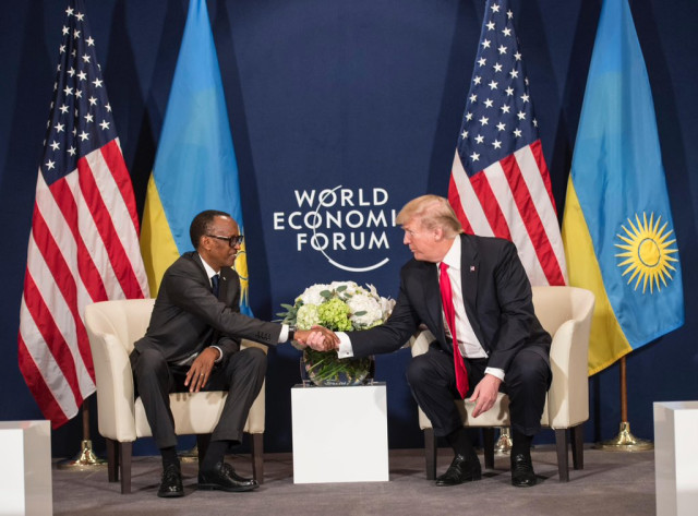 Two world leaders shaking hands at the World Economic Forum, with flags of the United States and Rwanda in the background, symbolizing international cooperation.