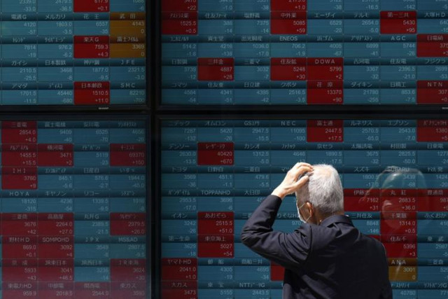 A person looks at an electronic stock board showing Japan's Nikkei 225 index at a securities firm