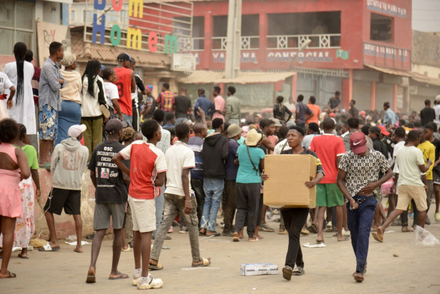 Residents carry items as looting erupted in the Kalemba 2 district of Luanda on July 28, 2025 during a general strike in the taxi sector declared for three days to protest against the rising prices of fuel. The looting happened after some 2,000 people pro