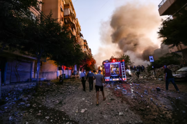 Photo of People and a fire truck rush to the scene of an Israeli air strike in Beirut