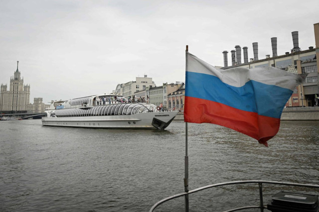 A Russian national tricolor flag flutters on a tourist boat as another boat passes by along the Moskva river in central Moscow on July 18, 2024