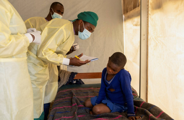 Dr. Tresor Wakilongo verifies the evolution of skin lesions on the ear of Innocent, suffering from Mpox at the treatment center in Munigi, following Mpox cases in Nyiragongo territory near Goma, North Kivu province, Democratic Republic of the Congo July 1