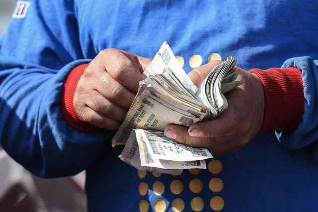 A worker counts money at a petrol station in Cairo on July 26, 2024