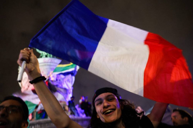 A participant holds a French flag during an election night rally following the first results of the second round of France's legislative election at Place de la Republique in Paris on July 7, 2024.