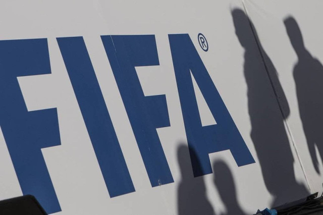 The shadows of spectators can be seen on a FIFA banner.