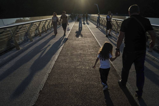 People walk on a pedestrian bridge during the sunset in city center of Kyiv, Ukraine, September 9, 2024.