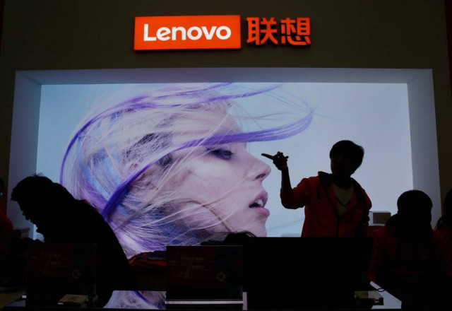 An employee gestures next to a Lenovo logo at Lenovo Tech World in Beijing, China November 15, 2019