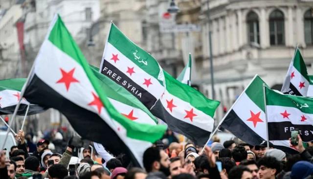 Photo of members of the Syrian community wave Syrian flags