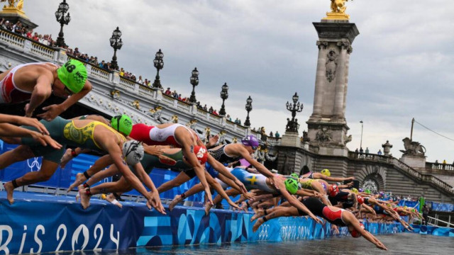 Triathletes dive into the River Seine at the start of the Olympic triathlon