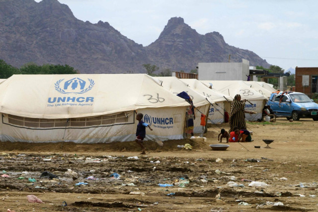 Sudanese already displaced by conflict, walk near tents at a makeshift campsite they were evacuated to following deadly floods in the eastern city of Kassala on August 12, 2024